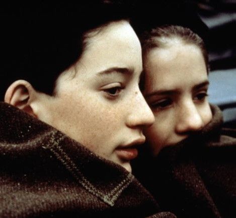 Primer plano de dos jovenes. Se están cubriendo con una bata del frío