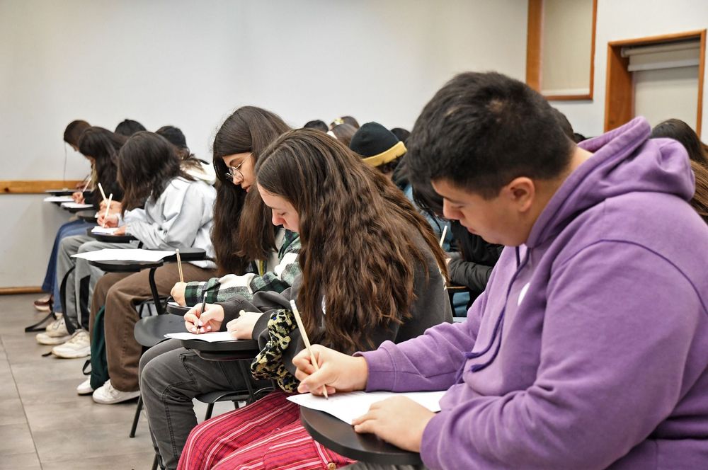 Grupo de estudiantes concentrados rindiendo una prueba.