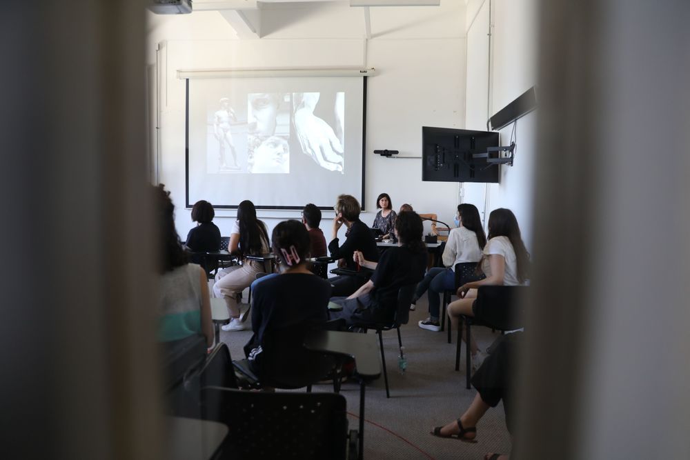 Grupo de estudiantes de Estética UC sentados en una sala de clase viendo una proyección.