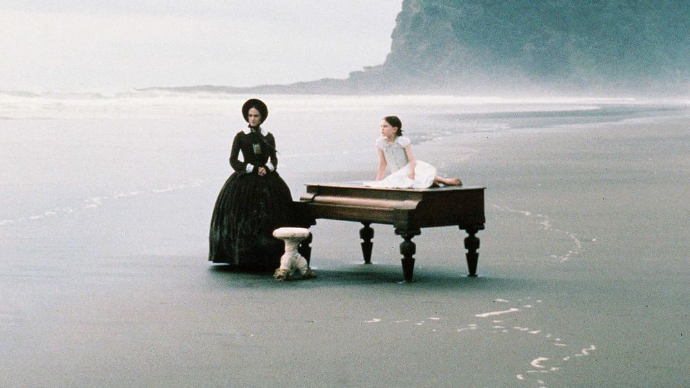Una niña sobre un piano y una mujer en una playa