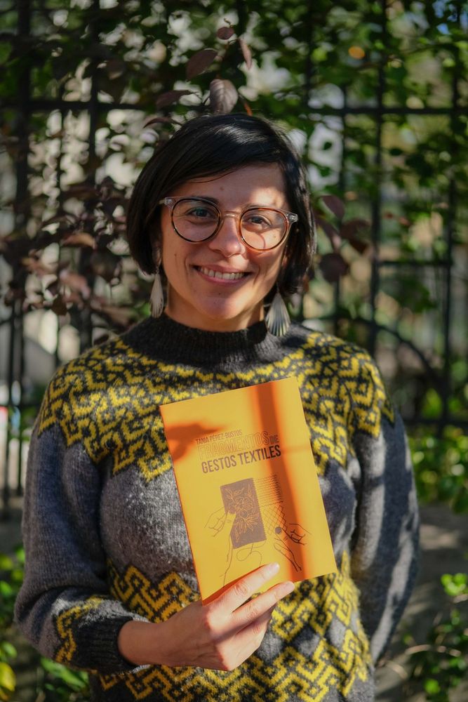 Fotografía de Tania Pérez Bustos junto a su libro Fragmentos de gestos textiles