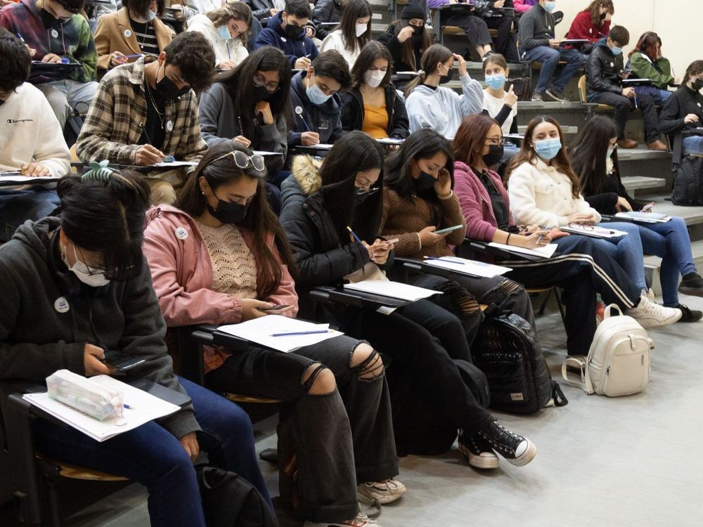 Jovenes estudiantes en un auditorio realizando una prueba