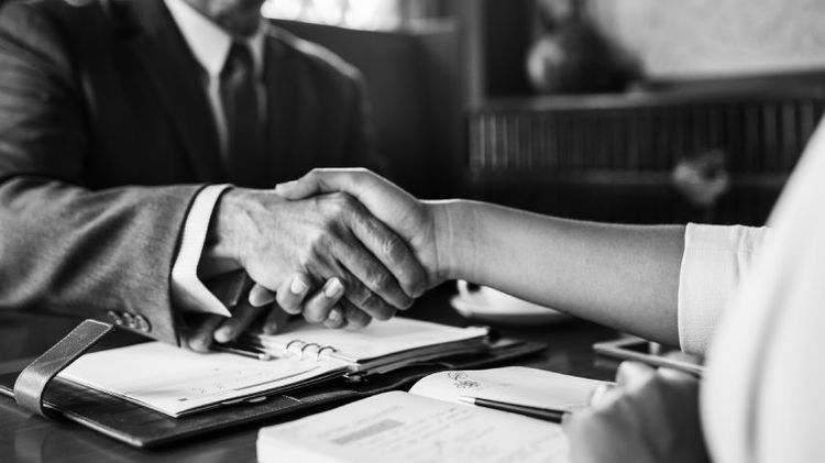 un hombre y una mujer dandose la mano como cerrando un trato