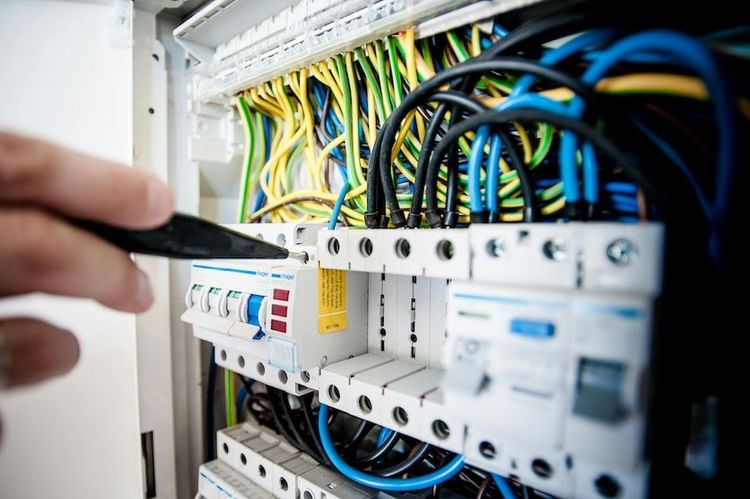 Foto de una mano que está trabajando en un sistema eléctrico.