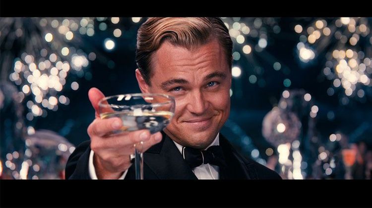 Imagen de una escena de la película "el gran gatsby" de 2013. Aparece el personaje interpretado por Leonardo Dicaprio brindando con una copa en la mano.