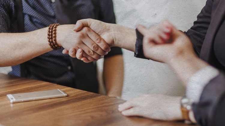 manos estrechándose en signo de acuerdo y una mano apuntando