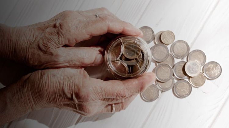 manos rodeando un frasco con monedas y monedas sueltas