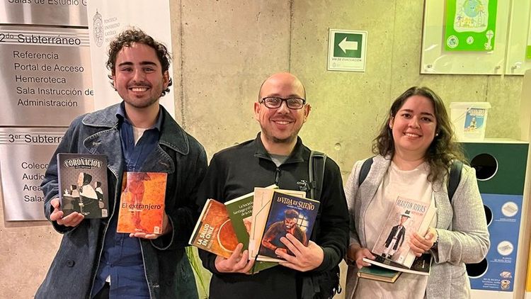 Fotografía de tres personas en la biblioteca con varios libros en sus manos. La foto pertenece a la actividad "Te regalo un libro" del año 2024.