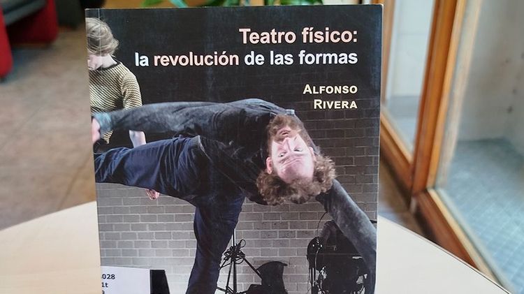 Fotografía del libro “Teatro físico: la revolución de las formas” de Alfonso Rivera exhibido sobre una mesa en la biblioteca, con una fotografía en portada de una figura en movimiento corporal.