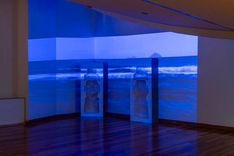 Exposición de arte: estatuas Moai en luz azul, plano general.