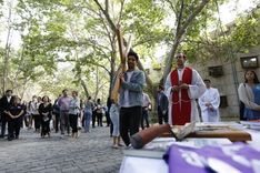 Un. joven cargando la cruz, acompañado por el sacerdote y la comunidad